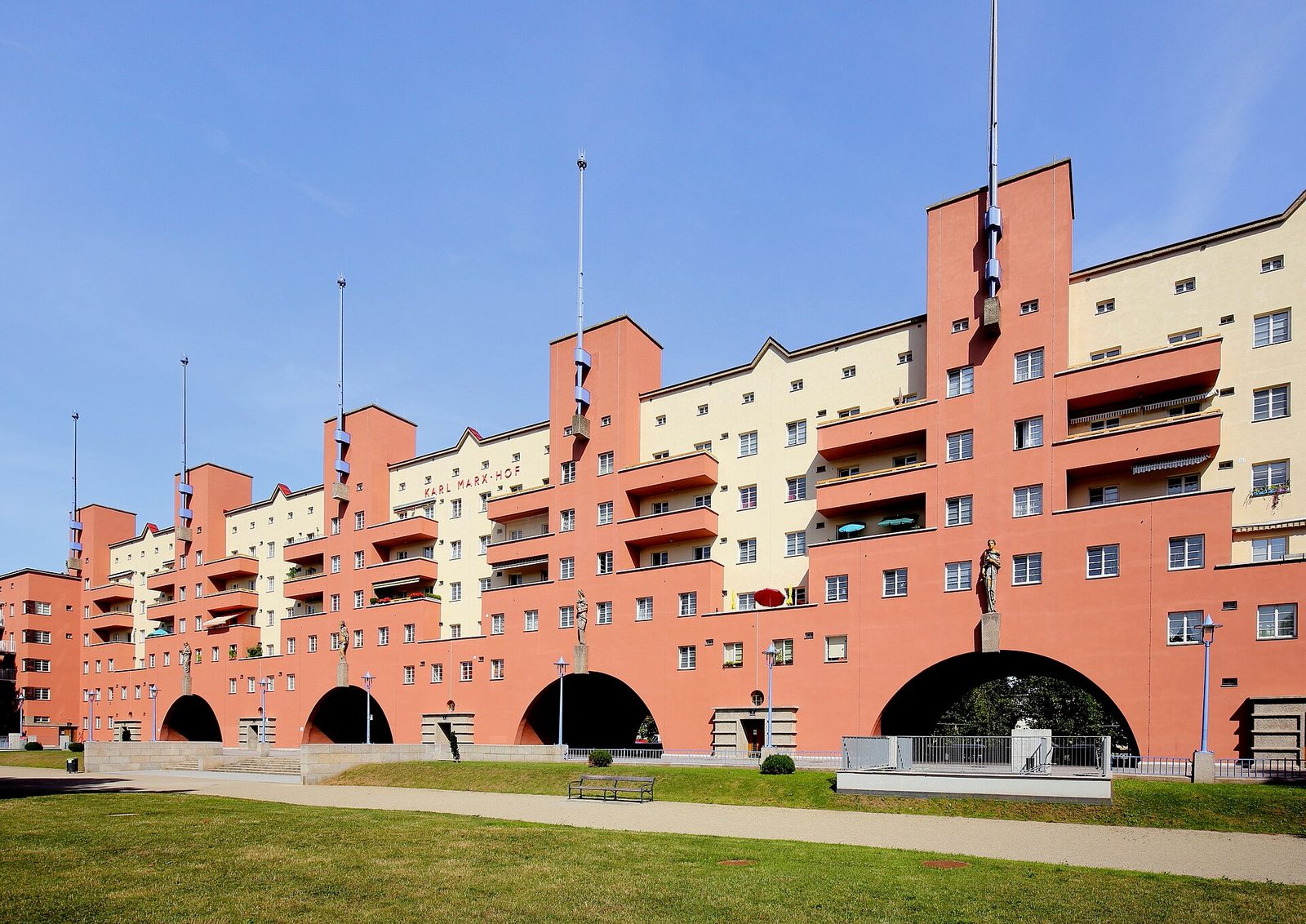Karl Marx Hof w Döbling — monumentalna fasada 1100-mieszkaniowego Gemeindebau z 1927 roku: czerwono-kremowe tynki, masywne arkady łukowe w parterze, flagowe maszty wzdłuż całej długości budynku. Fot. C.Stadler/Bwag, CC BY-SA 4.0, Wikimedia Commons