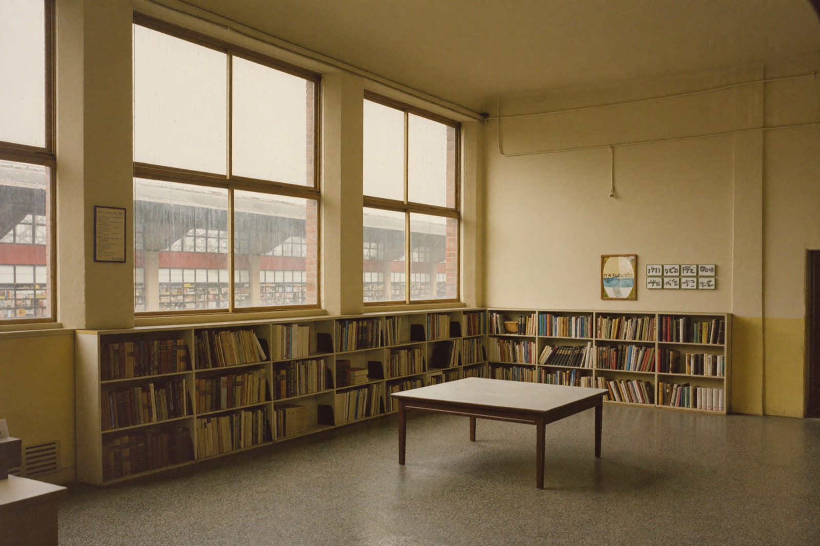 Czytelnia biblioteki urządzonej w dawnej poczekalni dworcowej, z regałami pod wysokimi oknami i widokiem na peron
