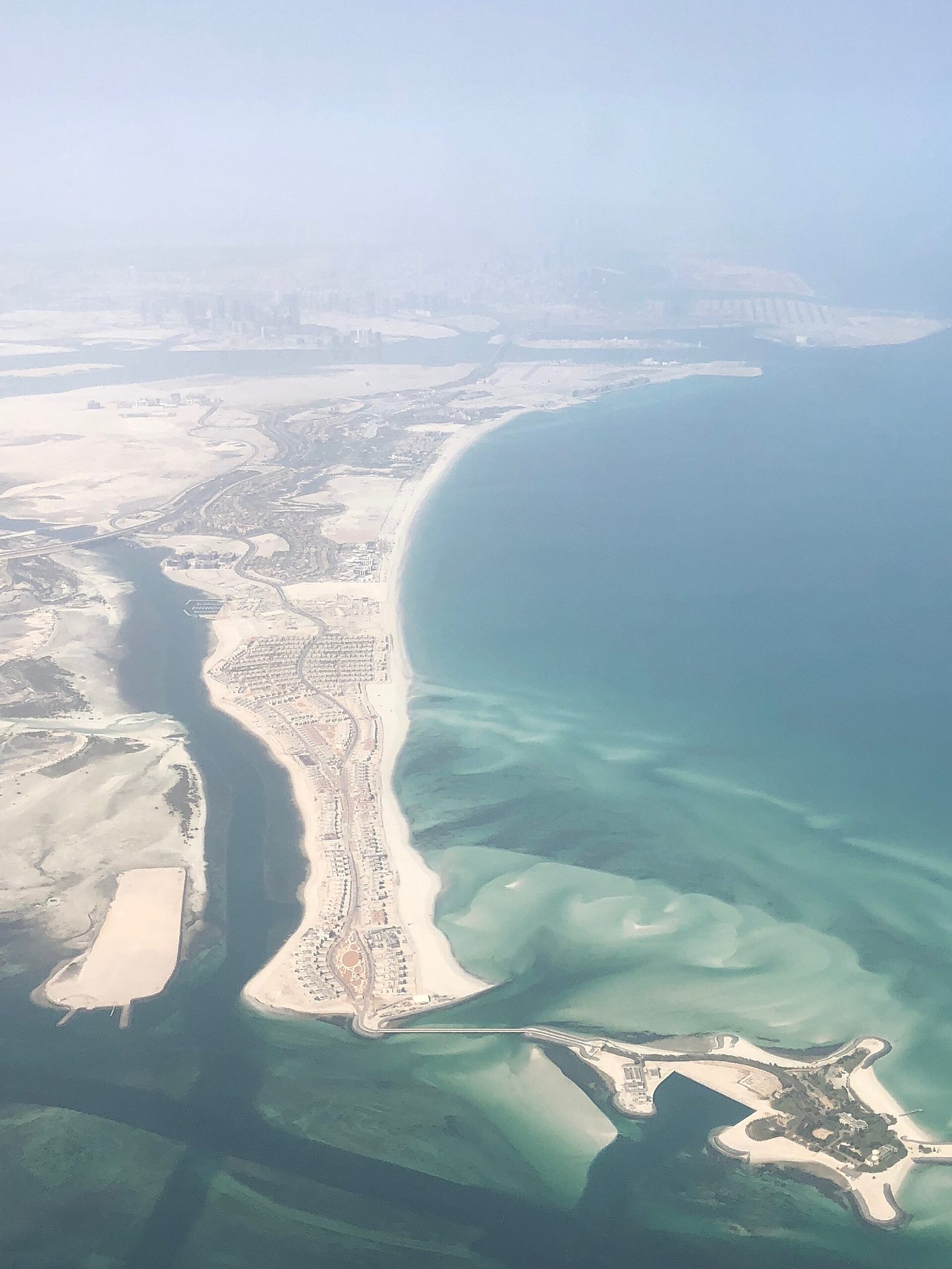 Widok z lotu ptaka na Wyspę Saadiyat (Saadiyat Island) w Abu Dhabi — sztuczna wyspa z zabudową mieszkalną i piaszczystym wybrzeżem, w tle skyline Abu Dhabi. Fot. Slywire, CC BY-SA 4.0, Wikimedia Commons