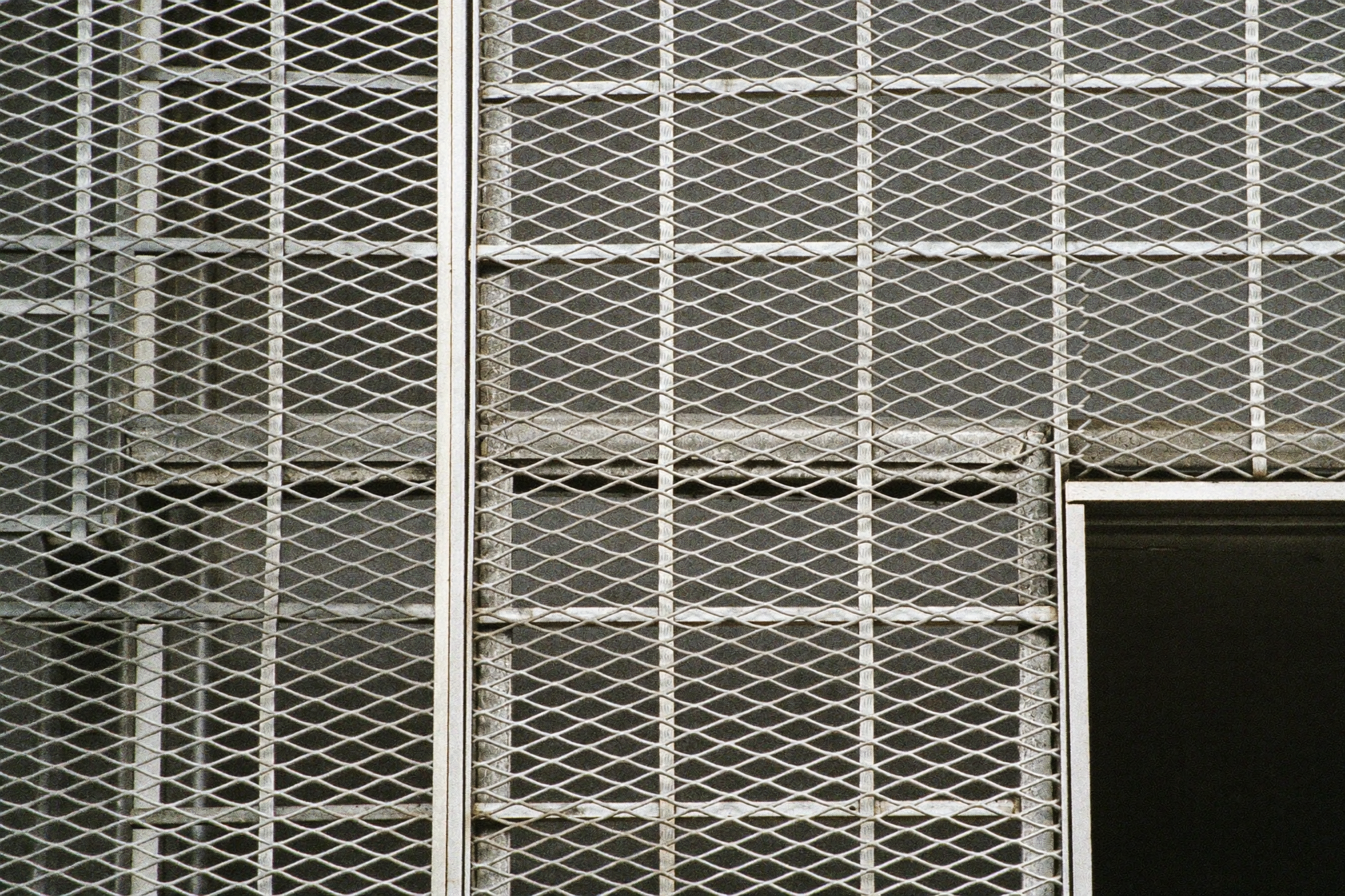 Zbliżenie na stalową siatkę diamentowego wzoru na elewacji — lustrzana metaliczna powierzchnia z geometrycznym wzorem, miękkie rozproszene światło