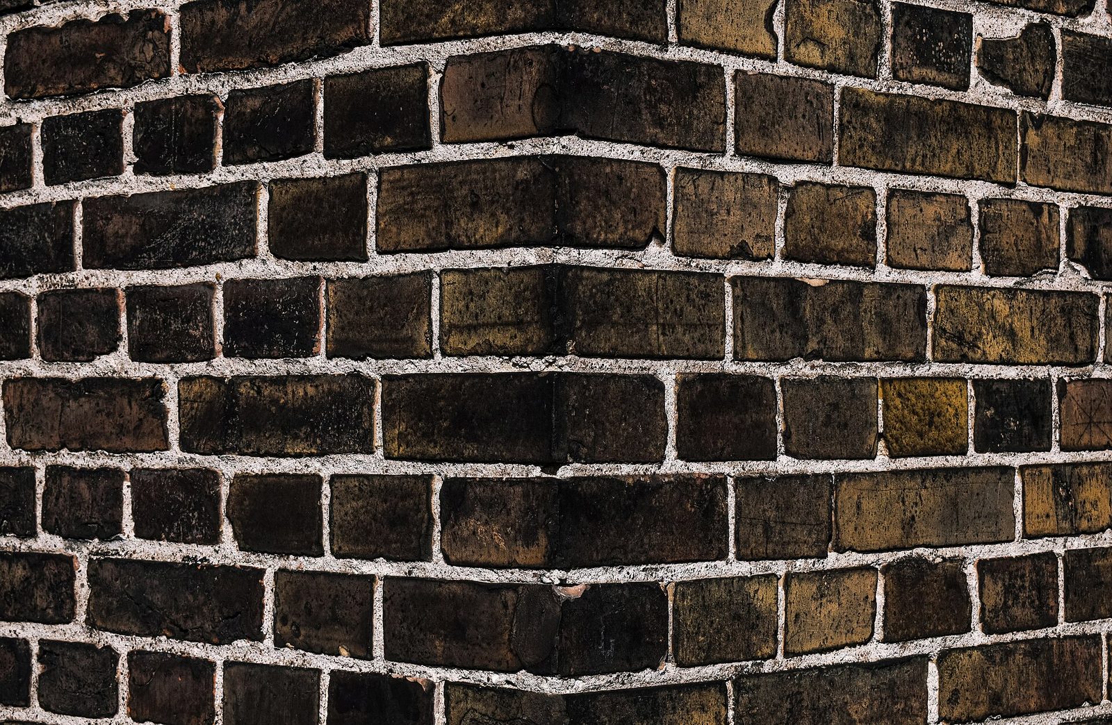 Zbliżenie na elewację z klinkierowej cegły ceramicznej — ciemne, patynowane cegły z białymi spoinami, lekko zakrzywiona powierzchnia narożnika. Fot. Radomianin, CC BY-SA 4.0, Wikimedia Commons