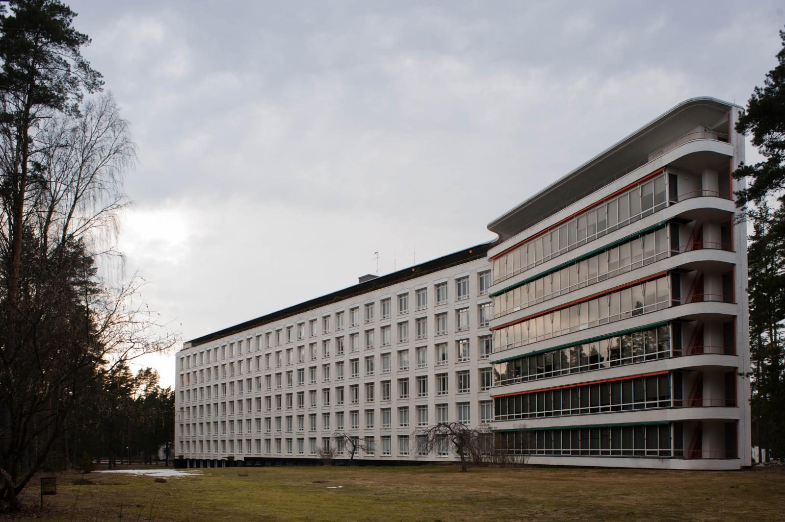 Sanatorium w Paimio (Finlandia, ok. 1929–1933) autorstwa Alvara Aalto — długi horyzontalny biały budynek wśród sosen, duże tarasy balkonowe, miękkie zachmurzone światło. Wpisane na listę UNESCO w 2026 r. Fot. Leon Liao from Barcelona, CC BY 2.0, Wikimedia Commons