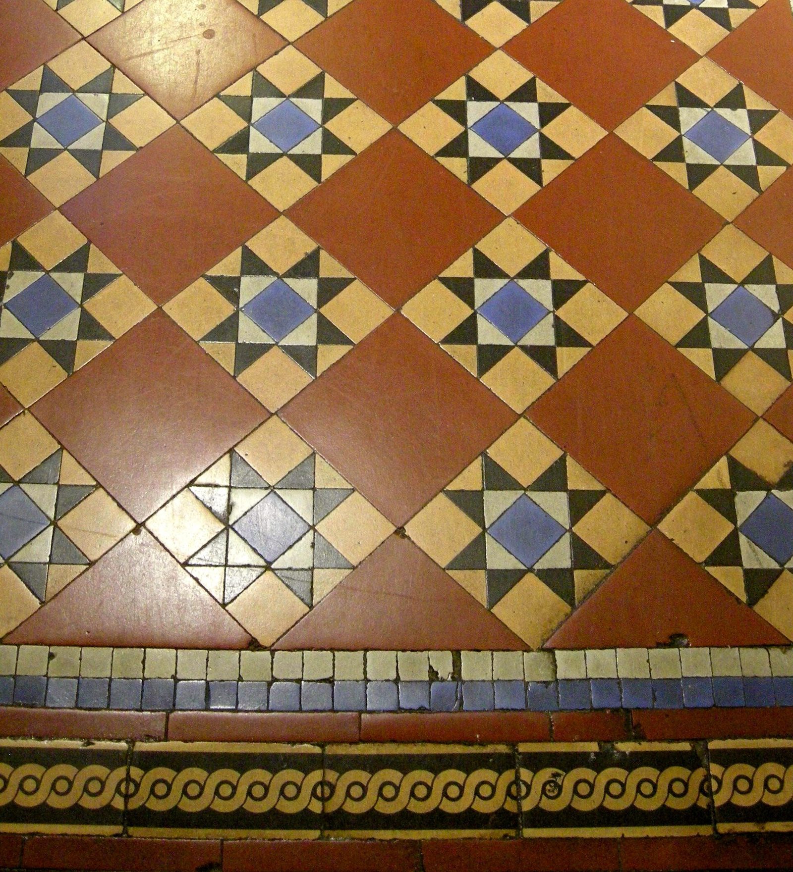 Geometryczna posadzka encaustyczna z XIX wieku w Bankfield Museum, Halifax — wzór z kafli w odcieniach terakoty, kremowego beżu i błękitu, widoczna bordura wzdłuż krawędzi. Fot. Linda Spashett Storye_book, CC BY 3.0, Wikimedia Commons